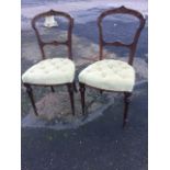 A pair of Victorian walnut chairs with carved spade shaped backs above button upholstered seats,