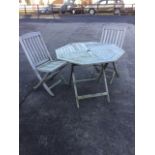 An octagonal teak garden table raised on folding legs, together with a pair of slatback chairs. (3)