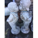 A pair of composition stone figures, the Jack & Jill children modelled in dungarees standing on