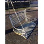 A wrought iron hanging garden bench with tubular rails to back & seat having scrolled arms,