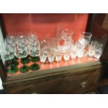 A set of twelve wine glasses with engraved bowls on green stems; other glass including