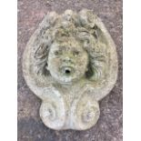 A composition stone wall fountain moulded as a cherub head framed by scrolls. (14.5in)