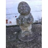 A composition stone gnome holding two pots, having hedgehog at his feet, standing on shaped