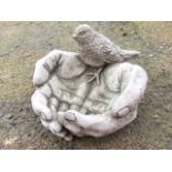 A composition stone birdbath modelled with cupped hands, the wrists perched with a bird. (8.5in)