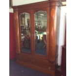 An Edwardian mahogany wardrobe with bowfronted corner pilasters inlaid with oval marquetry panels,