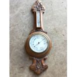 A Victorian oak barometer with foliate scroll carved frame, the circular enamelled dial with brass