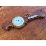 A barometer with scroll carving to frame, having silvered dial under bevelled glass with brass