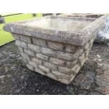A square composition stone planter with moulded rim, the tapering body cast with brickwork. (14in