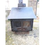 A Woodwarm cast iron multifuel stove with back boiler, the chimney outlet above shaped canopy and