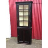 A stained nineteenth century corner cabinet with moulded cornice above an astragal glazed door,