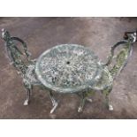 A circular cast aluminium garden table with two spadeback Victorian style chairs, with pierced