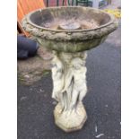 A composition stone birdbath with circular fluted bowl on three graces style column with octagonal