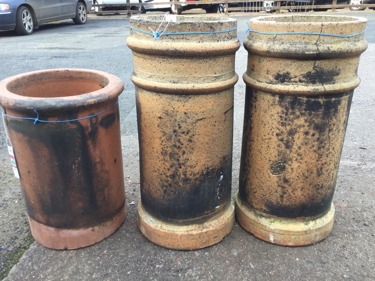 A pair of 2ft stoneware tubular chimney pots; and an 18in terracotta chimneypot with moulded rim. (