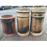 A pair of 2ft stoneware tubular chimney pots; and an 18in terracotta chimneypot with moulded rim. (