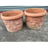 A pair of circular terracotta garden pots with moulded rims above embossed rose friezes. (15.5in x