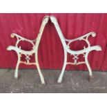 A pair of painted cast iron bench ends, with scrolled arms and channelled frames on sabre legs. (