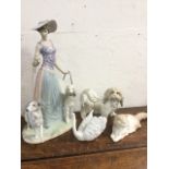 A large Lladro porcelain model of a lady with two dogs; a Lladro dog & swan; and a Nao cat. (4)