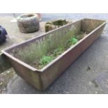 A 6ft rectangular cast iron trough with tapering sides and cushion rim, the end with partition. (