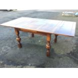 A 1930s oak draw-leaf dining table with panelled top on square column legs having fluted