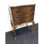 A serpentine fronted walnut cutlery cabinet, having three lined drawers mounted with ring handles,