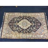 A rectangular Jaipur rug woven with oval floral medallion on ink blue field with conforming