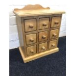 A dwarf chest of nine knobbed drawers supported on plinth, the rectangular moulded top with shaped