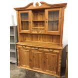 A pine dresser, the top with arched broken cornice above an open compartment and twin small