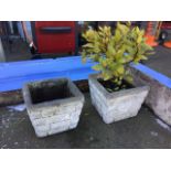 A pair of square composition stone planters, the pots cast with angled sides of faux brickwork. (