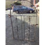 A wrought iron garden gate with scrolled decoration in arched frame. (32in x 53in)