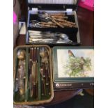 A set of brass cutlery with hardwood handles in baize lined cane tray; a set of stainless steel