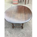 An oval elm coffee table, the top with drop leaves raised on bobbin turned legs and stretchers