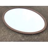 An Edwardian oval mahogany framed mirror with bevelled plate. (33.5in)