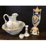 A Devon Ware jug & basin wash set with candlestick and trinket pot, decorated with pastel flowers;