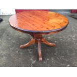 A circular Victorian style pine dining table, the telescopic top with integral spare leaf