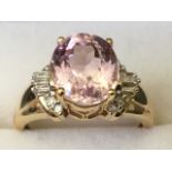 A 14ct gold kunzite ring, the oval claw set kunzite stone framed by baguette cut and circular