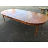 A mahogany dining table with four spare leaves, the top with D ends and channelled edge above a