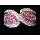 A 9ct white gold ruby and diamond ring, with shaped pave set ruby panels framed by crossover diamond