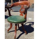 A late Victorian captains chair, the revolving seat with rounded back and scrolled arms having