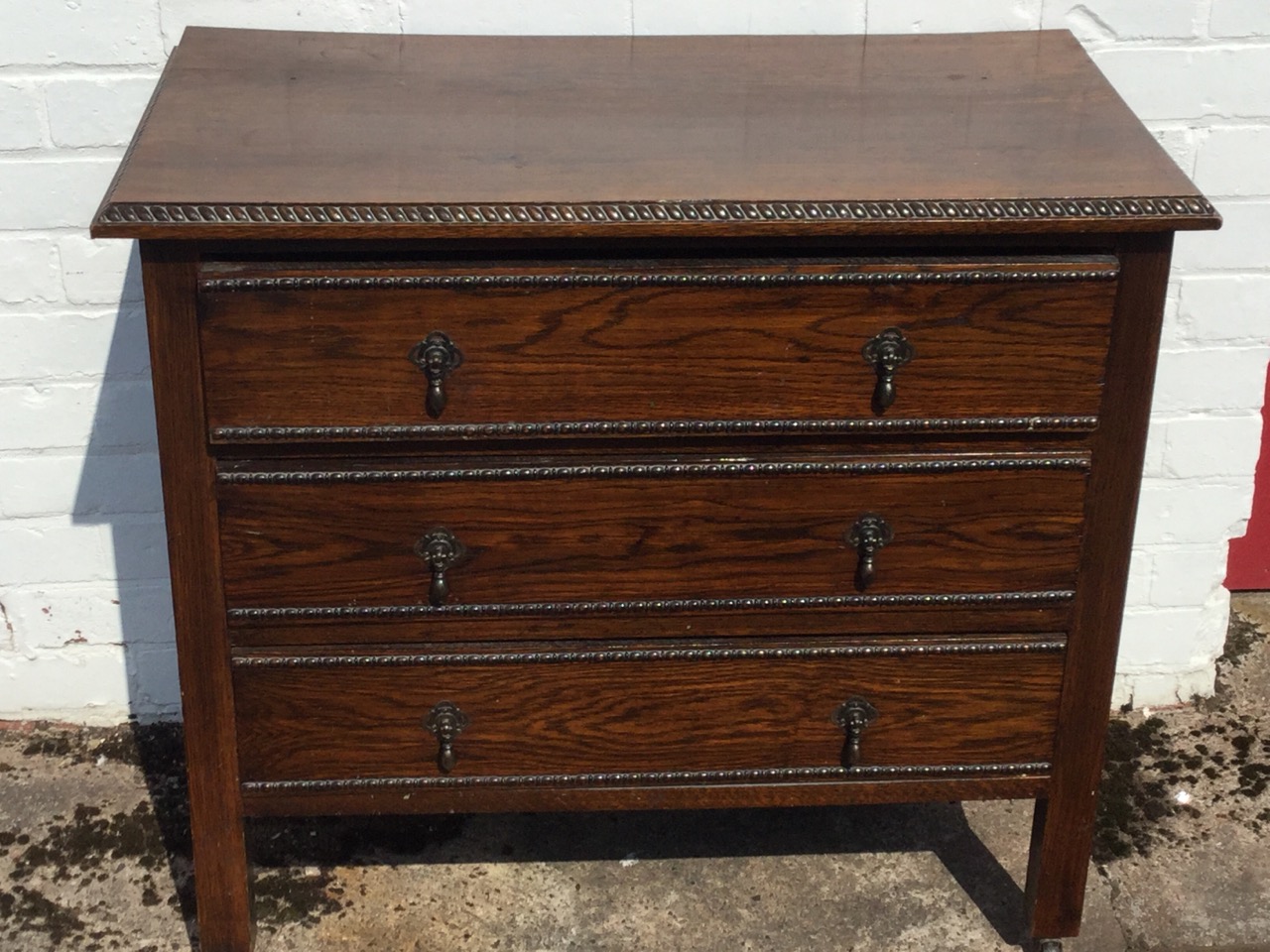 A George VI oak chest of three long drawers with applied bobbin & twisted mouldings, the drawers