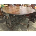 An oval nineteenth century oak drop-leaf dining table, formerly with frieze drawer, raised on bobbin