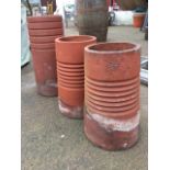 A pair of ribbed tapering terracotta chimney pots (19in); and another taller and similar moulded