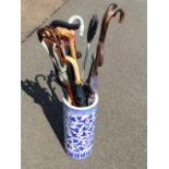 A tubular blue & white floral decorated ceramic umbrella stand containing sticks, canes,