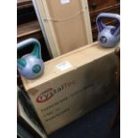 A boxed Crystaltec exercise bike with 10kg flywheel - unused; and two weights - 12 & 10kg. (3)