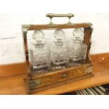 A Victorian oak tantalus with silver plated mounts, having three square cut glass decanters with