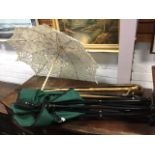 Four walking sticks - one with hallmarked silver mount; a lacework style parasol; and a modern