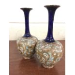 A pair of Royal Doulton stoneware vases with slender blue glazed necks and flared rims above foliate