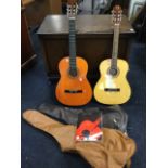 Two classical guitars, both with soft cases; and a classical guitar instruction book. (A lot)