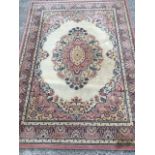 A Belgian Pacific oriental style wool rug woven with oval floral medallion on fawn field with