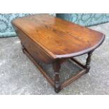 An Old Charm oval oak coffee table, the moulded top with two drop-leaves and shaped end aprons,