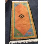 A contemporary Indian Kayam wool rug, woven with orange field having central diamond medallion,